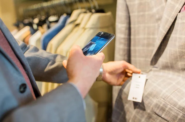 Close up of man with smartphone at clothing store — Stock Photo, Image