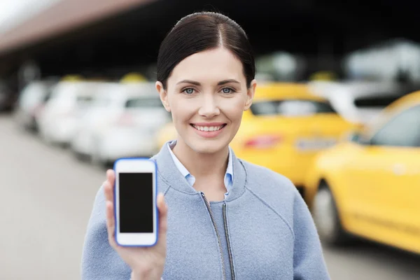 Smiling woman showing smartphone over taxi in city — Stock Photo, Image