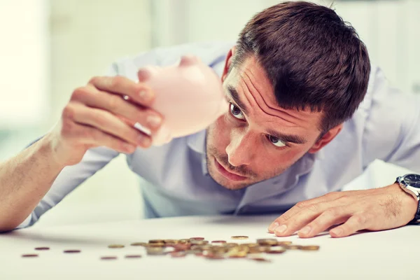 Businessman with piggy bank and coins at office Royalty Free Stock Photos