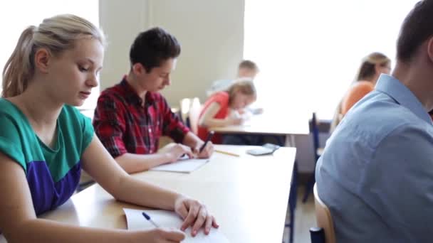 Estudiantes con cuadernos prueba de escritura en la escuela — Vídeo de stock