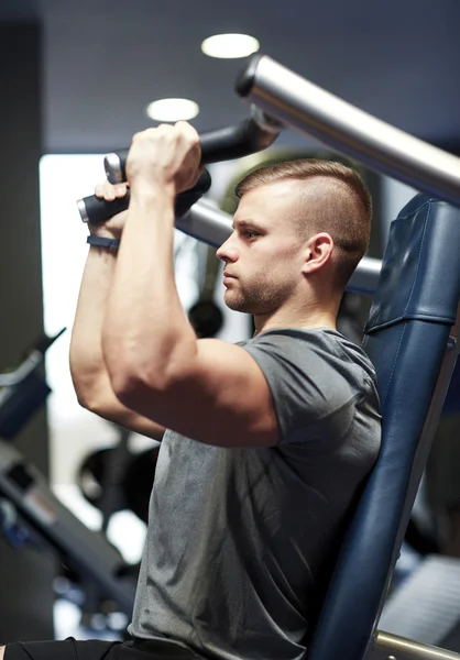 Hombre ejercitando y flexionando los músculos en la máquina de gimnasio — Foto de Stock