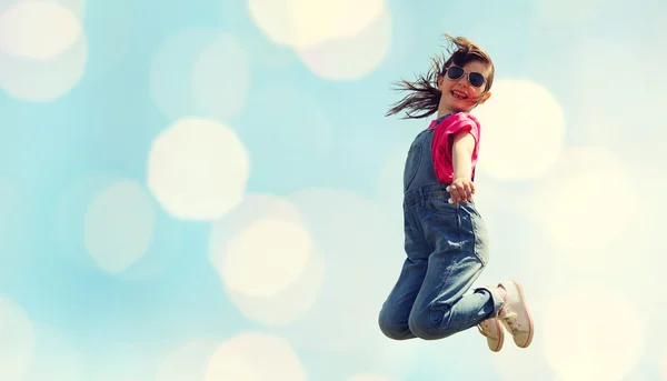 Happy little girl jumping high over blue lights — Stock Photo, Image