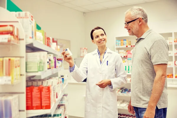 Farmacêutico mostrando droga para homem idoso na farmácia — Fotografia de Stock