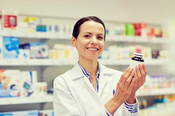 Farmacéutica mujer feliz con frasco de medicamentos en la farmacia — Foto de Stock