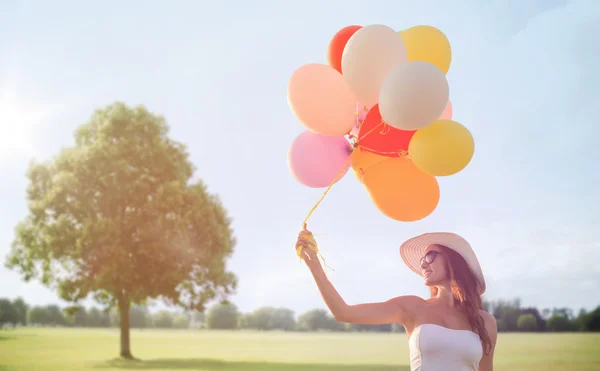 Gülümseyen güneş gözlüğü balonlarla genç kadın — Stok fotoğraf