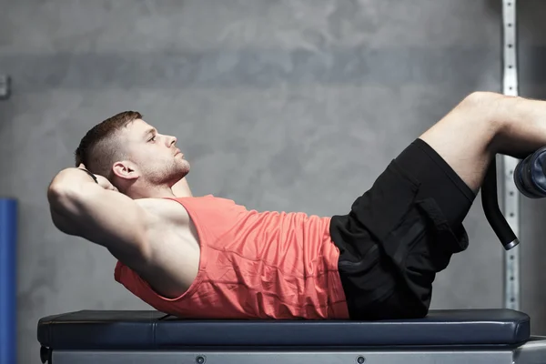 Молодой человек делает упражнения брюшной полости в тренажерном зале — стоковое фото