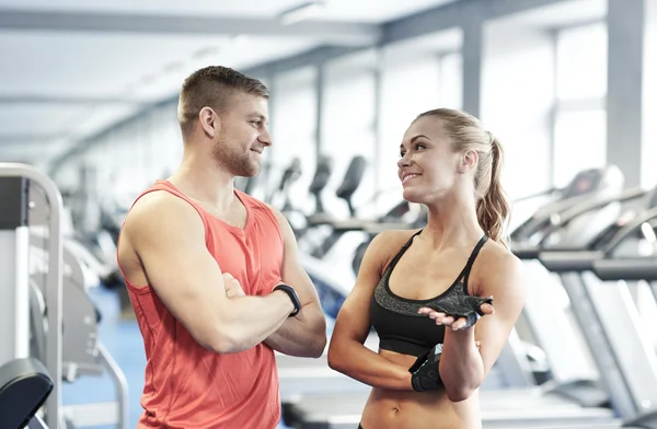 Glimlachende man en vrouw praten in de sportschool — Stockfoto