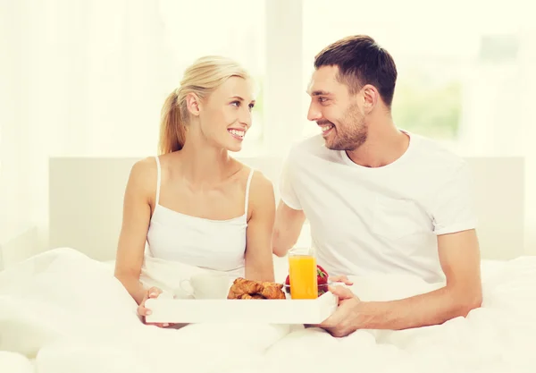 Casal feliz tomando café da manhã na cama em casa — Fotografia de Stock