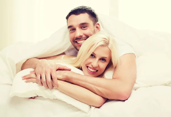 Casal feliz deitado na cama e abraçando em casa — Fotografia de Stock