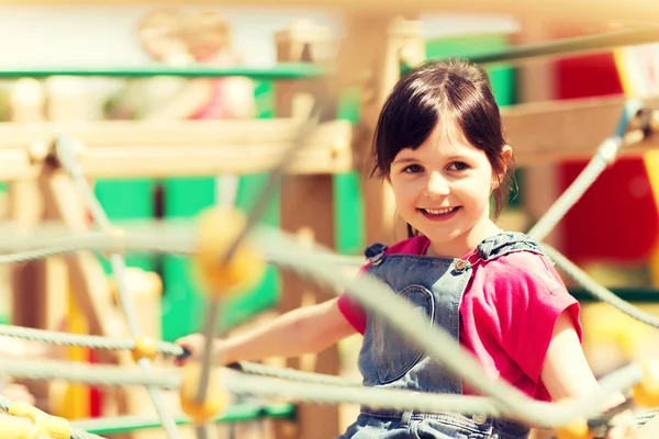 Fröhliches kleines Mädchen klettert auf Kinderspielplatz — Stockfoto