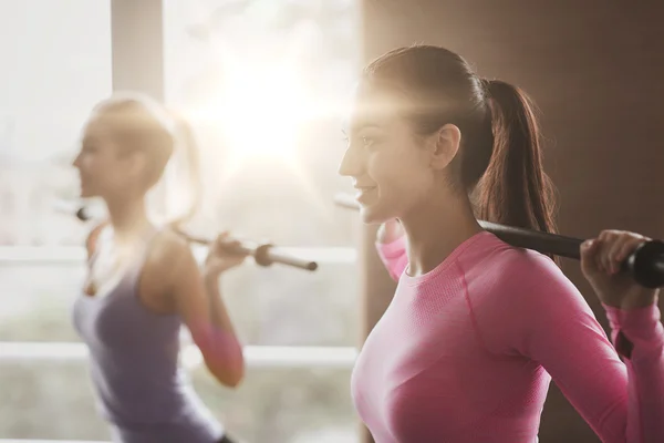 Grupp människor tränar med barer i gym — Stockfoto