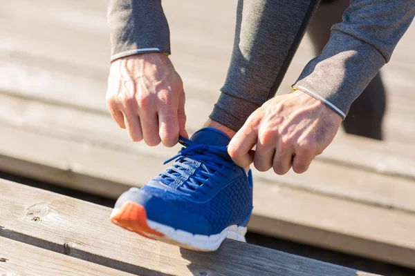 Gros plan d'un homme sportif attachant des lacets de chaussures à l'extérieur — Photo