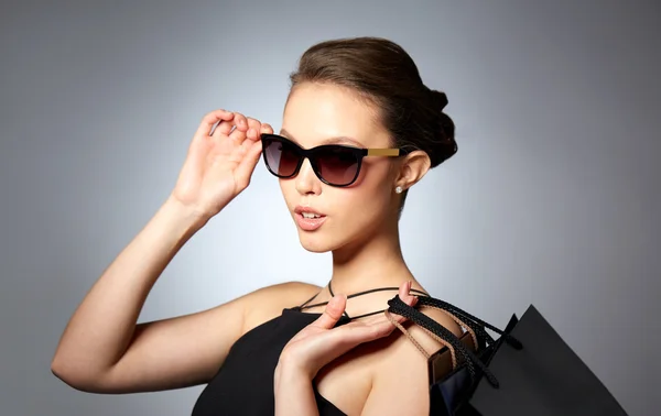 Felice donna in occhiali da sole neri con borse della spesa — Foto Stock