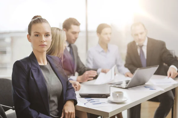 Zakenvrouw in kantoor met team op de rug — Stockfoto