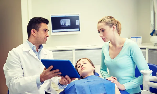 Dentista mostrando tableta PC a niña y su madre — Foto de Stock