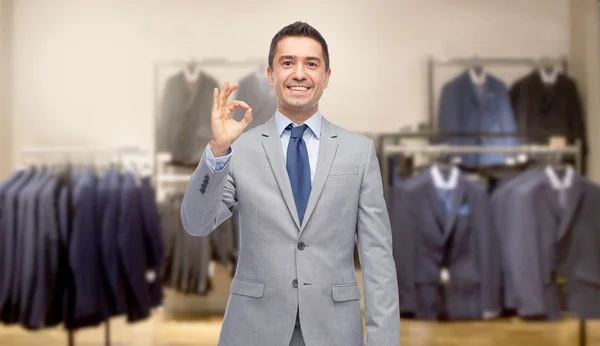 Happy businessman in suit over clothing store — Stock Photo, Image
