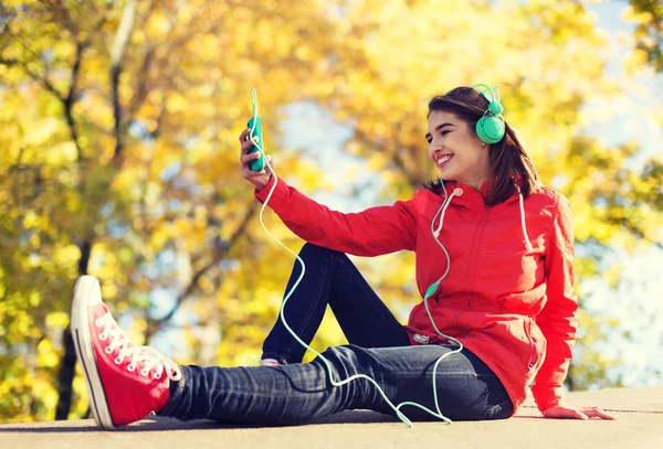 Gelukkig jonge vrouw met smartphone en hoofdtelefoons — Stockfoto