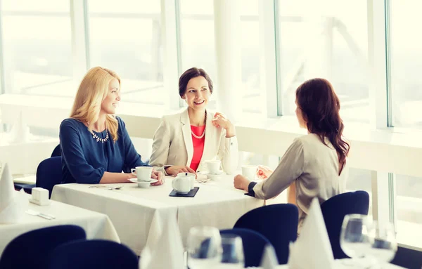 Women drinking coffee and talking at restaurant — Stock Photo, Image