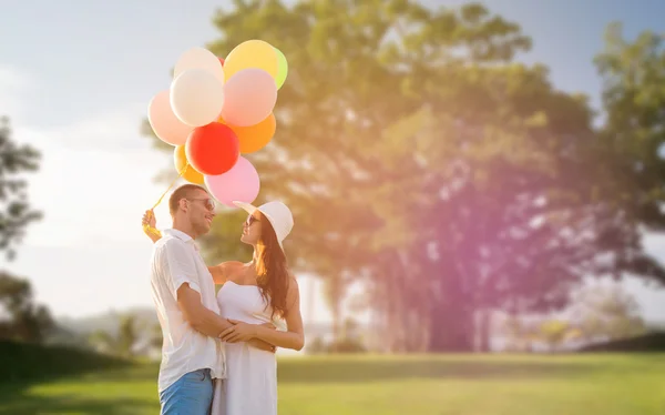 Casal sorridente com balões de ar ao ar livre — Fotografia de Stock