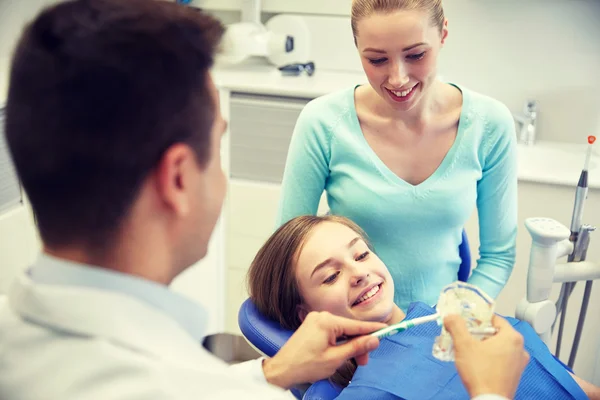 Glücklicher Zahnarzt zeigt geduldigem Mädchen Zahnbürste — Stockfoto