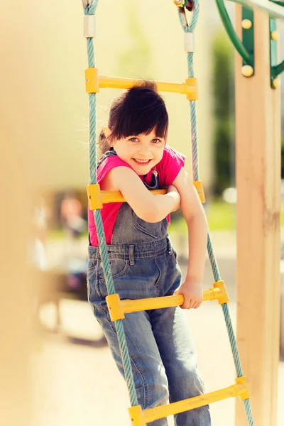 Fröhliches kleines Mädchen klettert auf Kinderspielplatz — Stockfoto