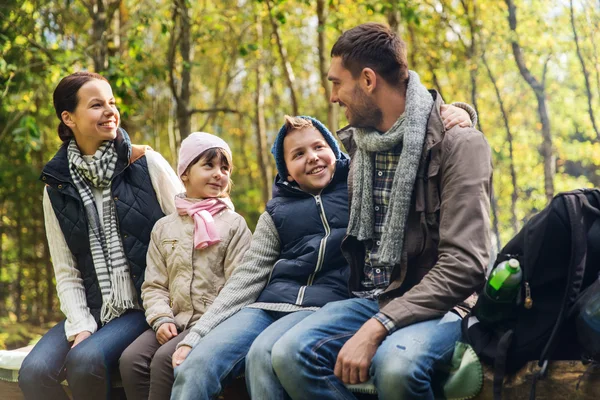 Happy family sitting on bench and talking at camp — Stock Photo, Image