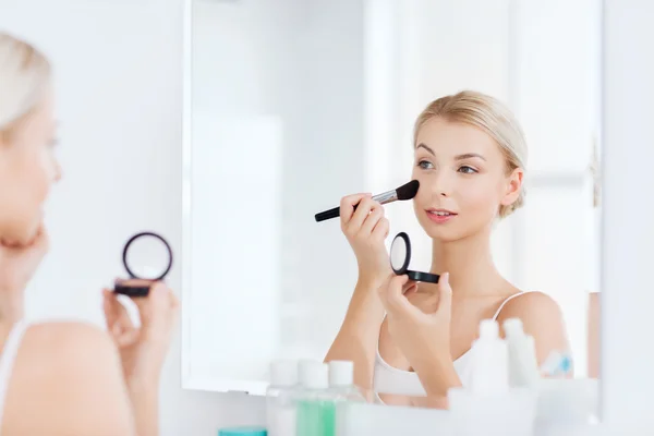 Mulher com escova de maquiagem e blush no banheiro — Fotografia de Stock