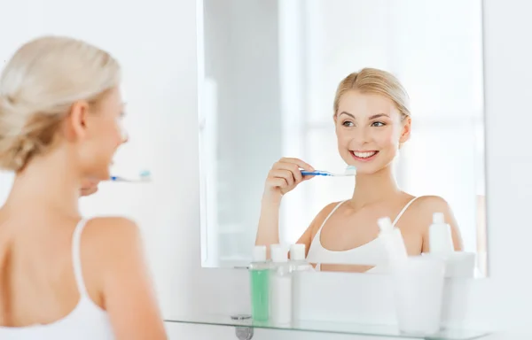 Mulher com escova de dentes limpeza dentes no banheiro — Fotografia de Stock