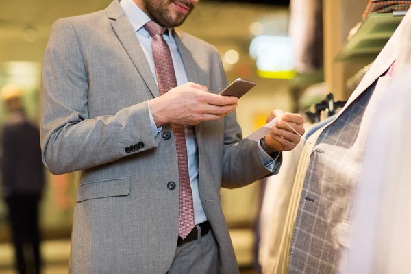 Close up of man with smartphone at clothing store — Stock Photo, Image