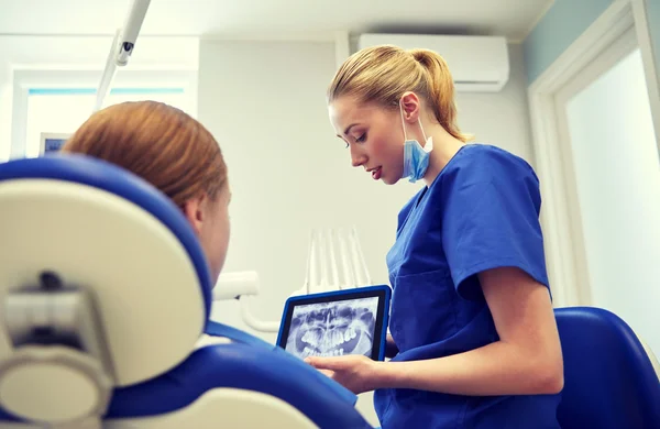 Dentista que muestra rayos X en el comprimido pc a la niña paciente —  Fotos de Stock