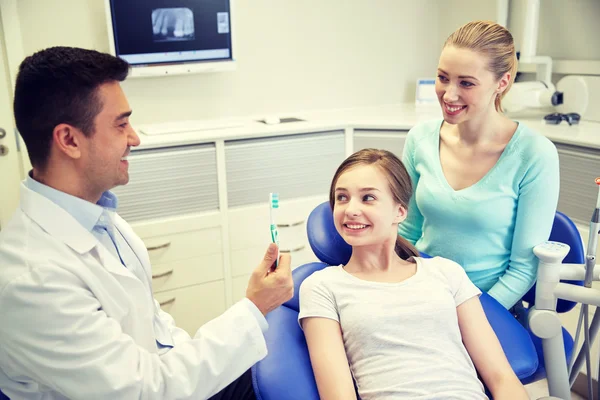 Glücklicher Zahnarzt zeigt geduldigem Mädchen Zahnbürste — Stockfoto