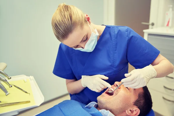 Dentista femenino revisando los dientes de los pacientes masculinos — Foto de Stock