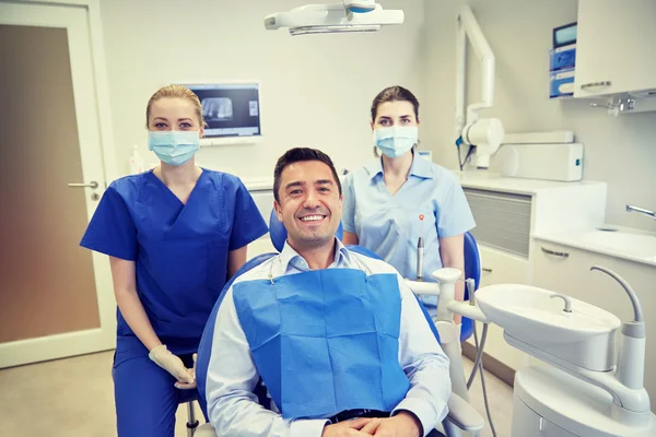 Щасливі жінки-стоматологи з пацієнтом чоловічої статі в клініці — стокове фото