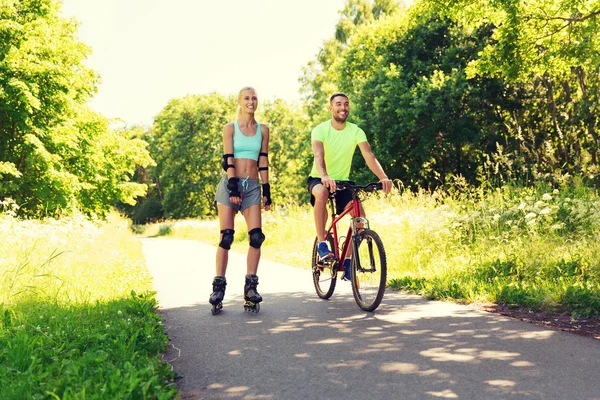 Glückliches Paar mit Rollerblades und Fahrrad — Stockfoto