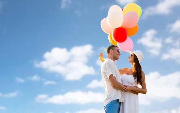 Casal sorridente com balões de ar ao ar livre — Fotografia de Stock