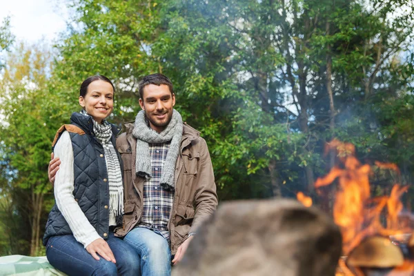 Heureux couple assis sur le banc près du feu de camp — Photo