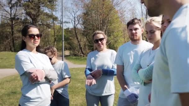 Група волонтерів, що слухають наставника в парку — стокове відео