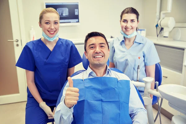 Dentistas mujeres felices con el hombre paciente en la clínica —  Fotos de Stock