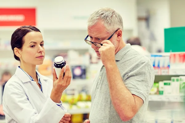 Farmacêutico mostrando droga para homem idoso na farmácia — Fotografia de Stock
