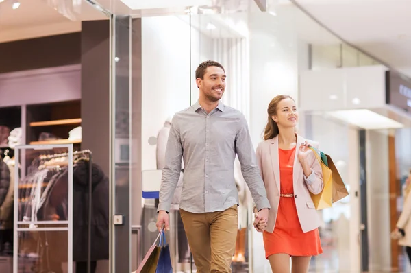 Feliz jovem casal com sacos de compras no shopping — Fotografia de Stock