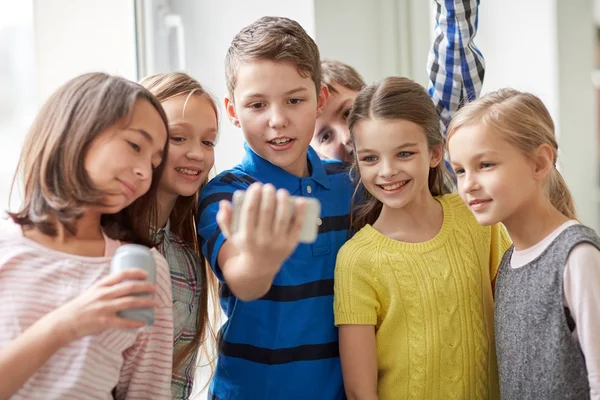 Grupo de niños de la escuela con teléfonos inteligentes y latas de refrescos — Foto de Stock