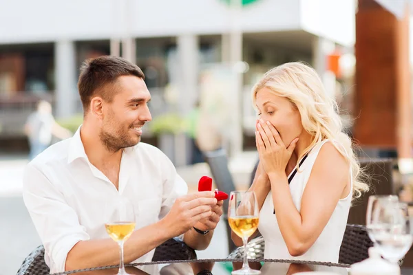 Casal feliz com anel de noivado e vinho no café — Fotografia de Stock