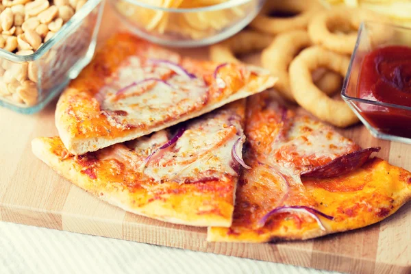 Close up of pizza and other snacks on wooden table — Stok fotoğraf