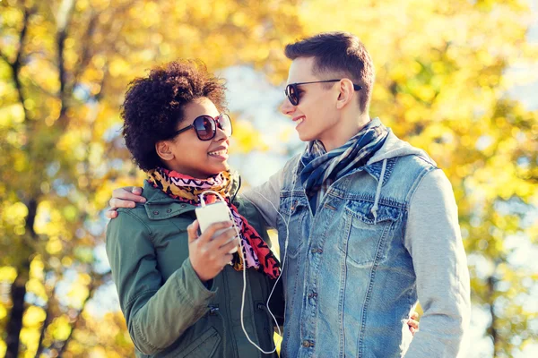 Smiling couple with smartphone and earphones — Stock Photo, Image