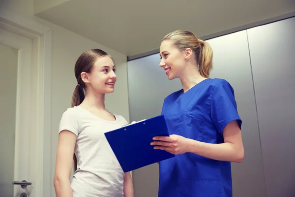 Smiling nurse with clipboard and girl at hospital — Stock Photo, Image
