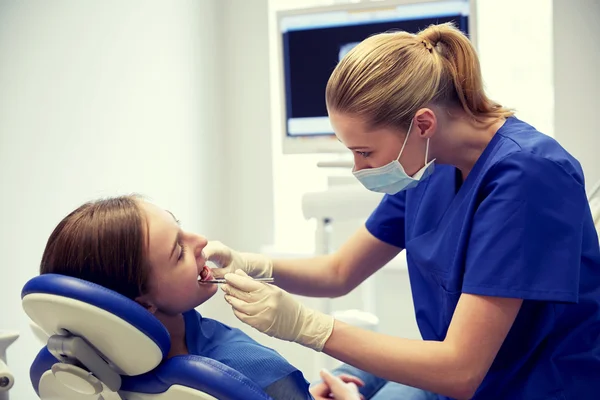 Dentista femenino chequeando dientes de niña paciente — Foto de Stock