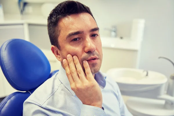 Homem com dor de dente e sentado na cadeira dental — Fotografia de Stock