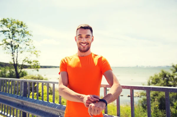 Jeune homme souriant avec montre-bracelet intelligente au bord de la mer — Photo