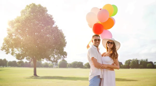 Smiling couple with air balloons outdoors — Stock Photo, Image