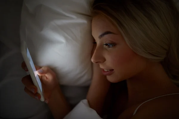 Jeune femme avec smartphone dans le lit à la maison chambre — Photo